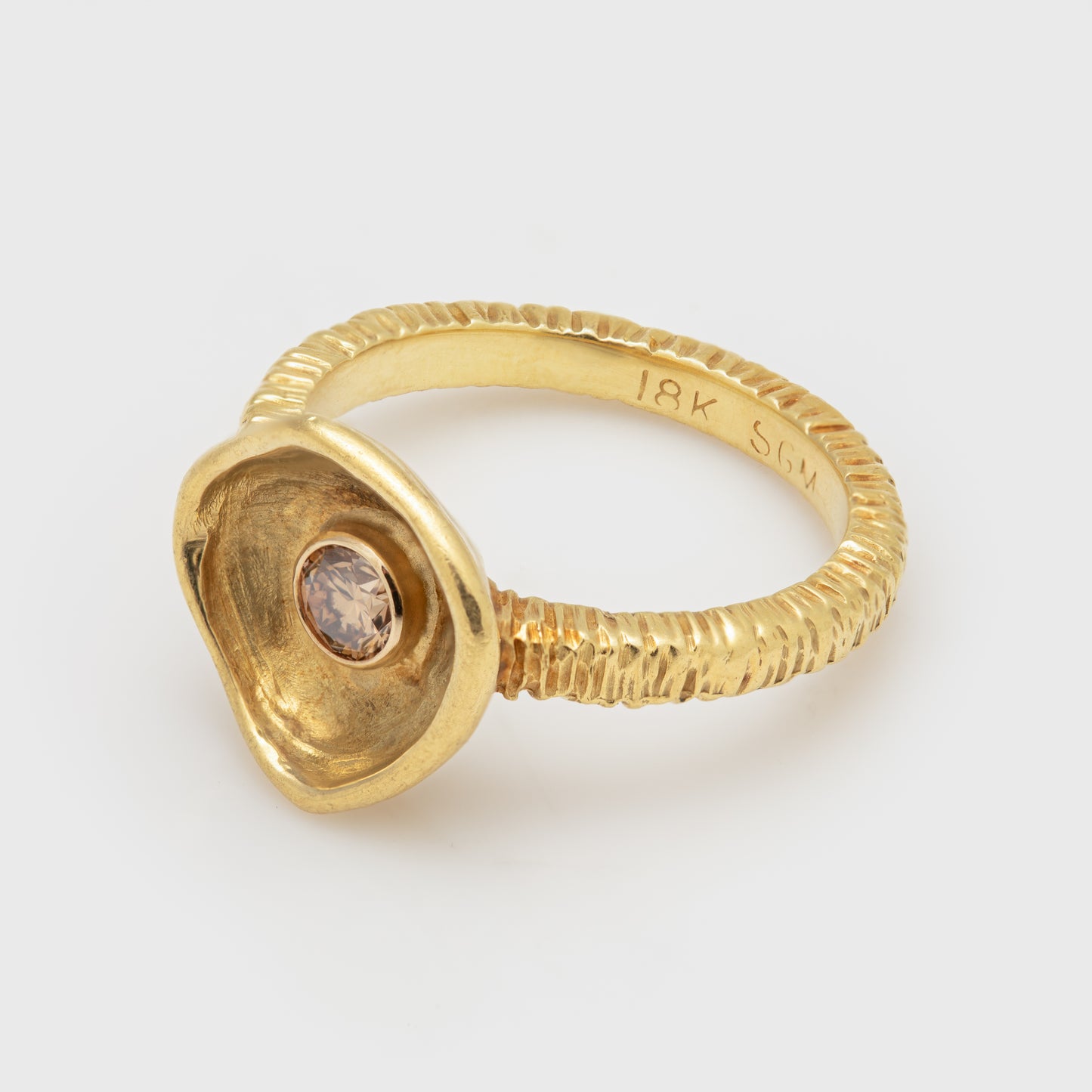 Close-up of an 18k yellow gold ring with a round cognac diamond.