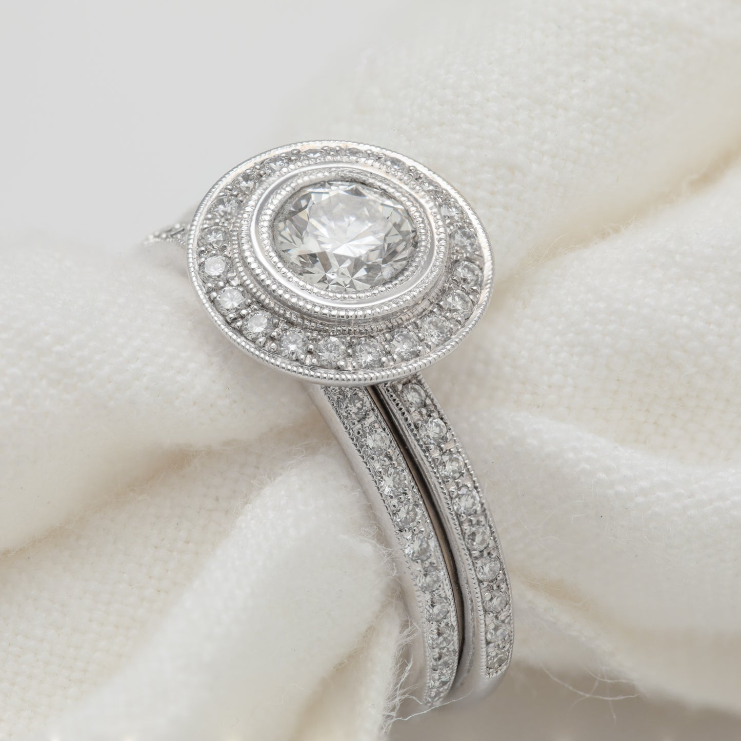 Close-up of an 18k white gold ring with a Hearts on Fire diamond and diamonds, including a matching eternity band.
