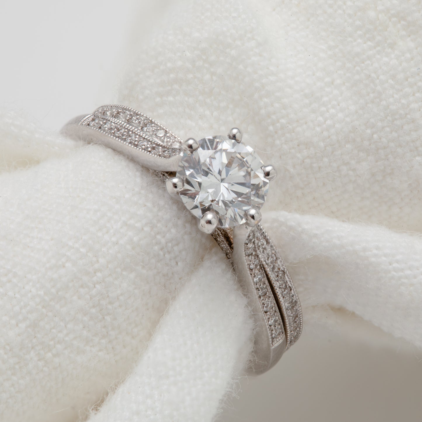 Close-up of an 18k white gold ring with diamond and diamond accents. A matching eternity band is included.