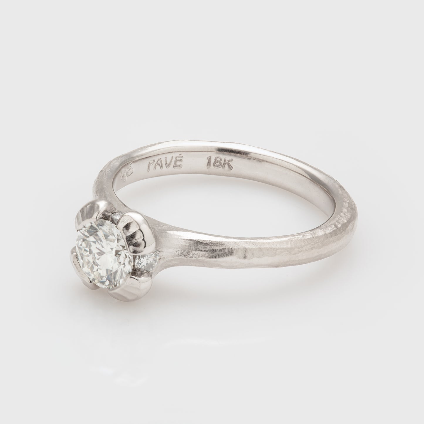 Side view of an 18k white gold ring with a diamond and a redwood bark textured shank.