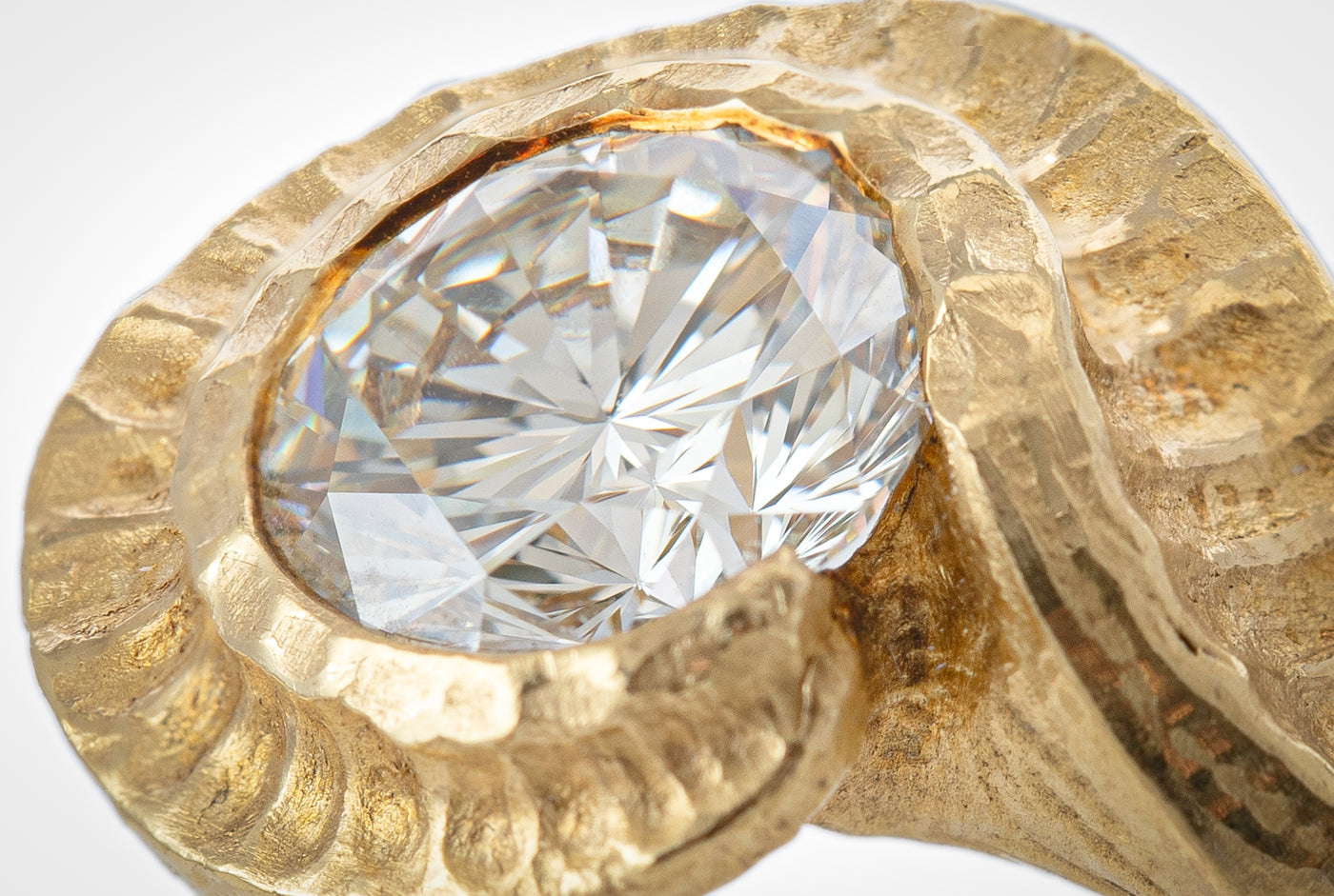Close up view of round white gem set in yellow metal