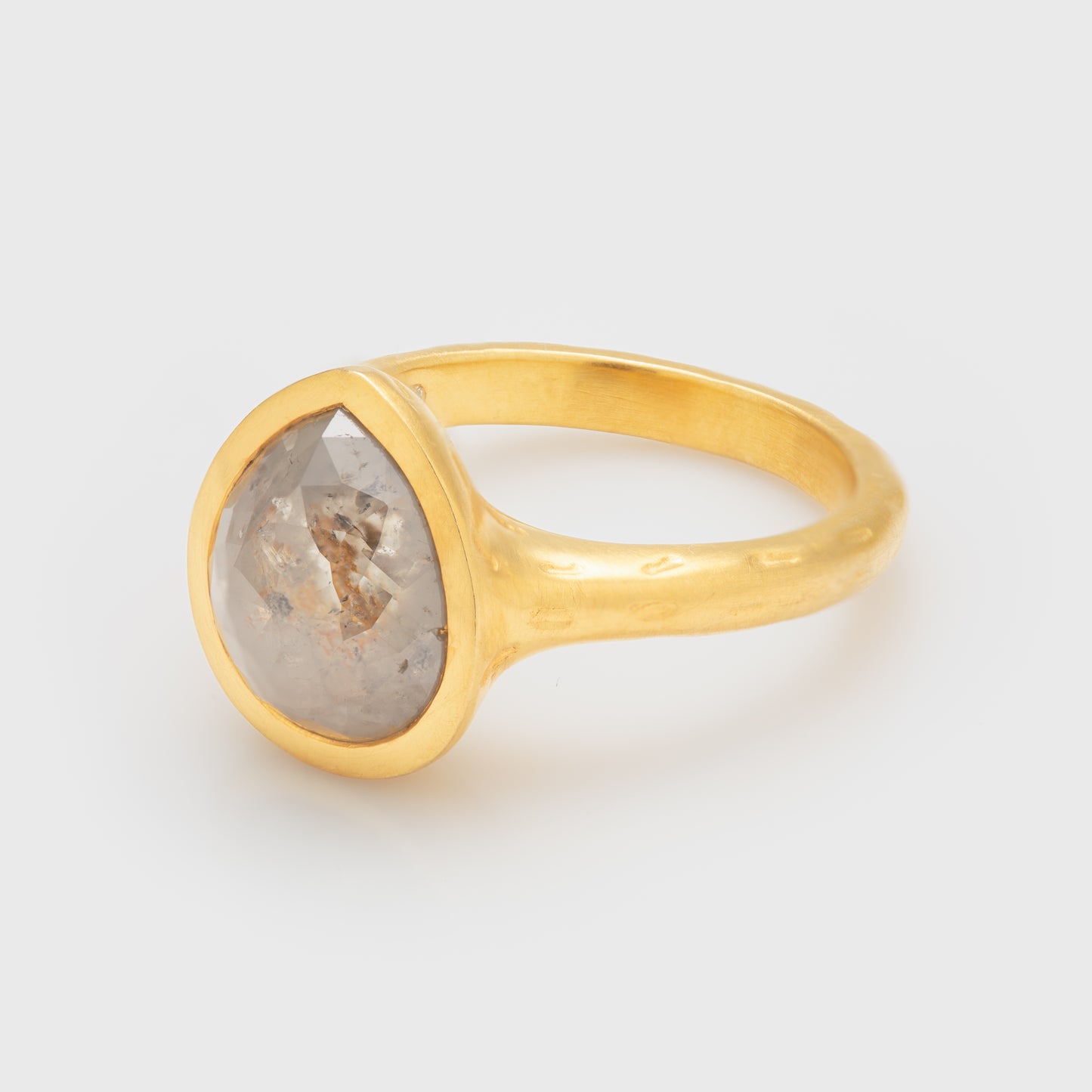 Side view of a 18k yellow gold ring with a drop-shaped rustic diamond.