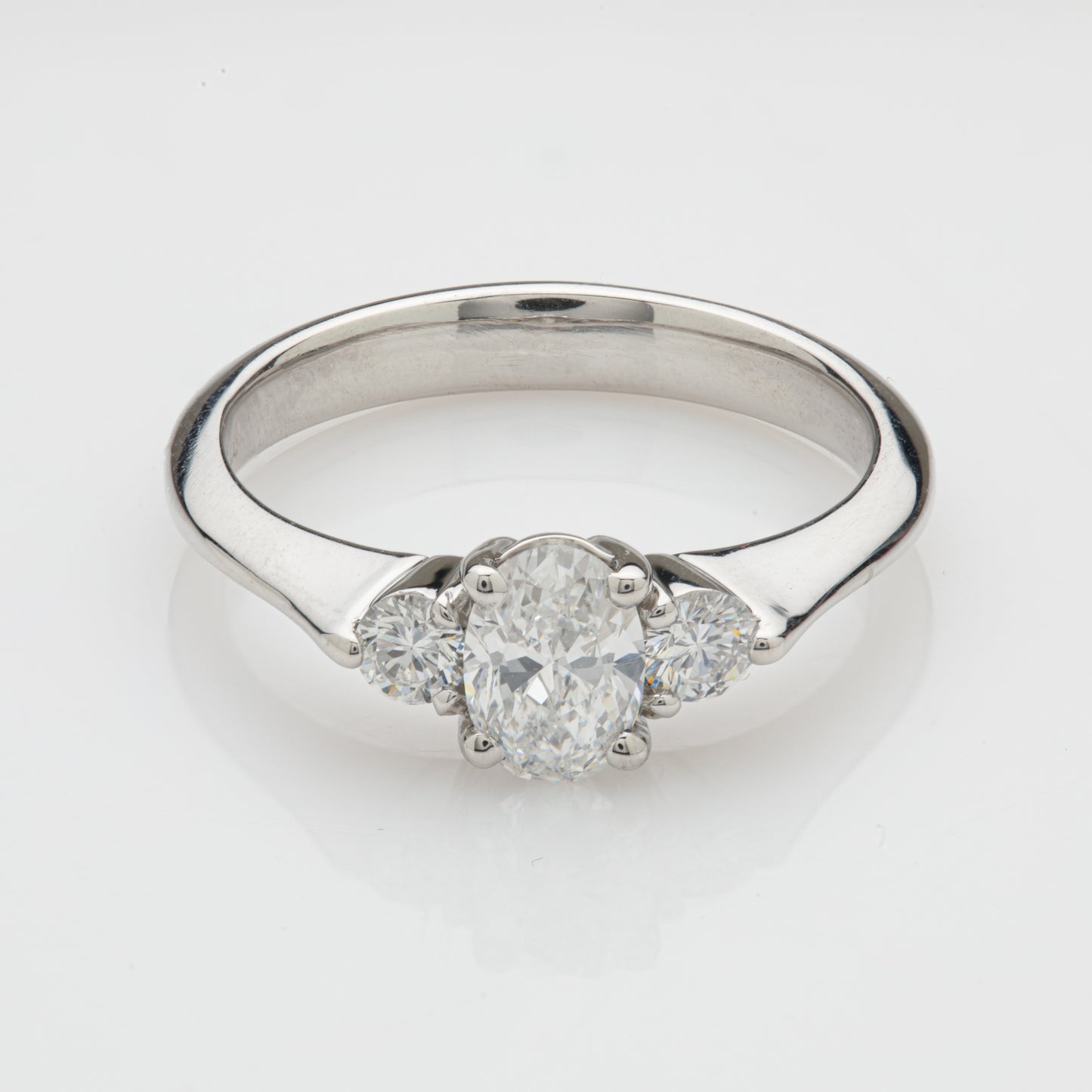 Close-up of a platinum ring with an oval diamond and diamond accents.