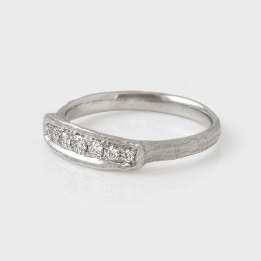 Platinum ring with diamonds on a light gray background, side view