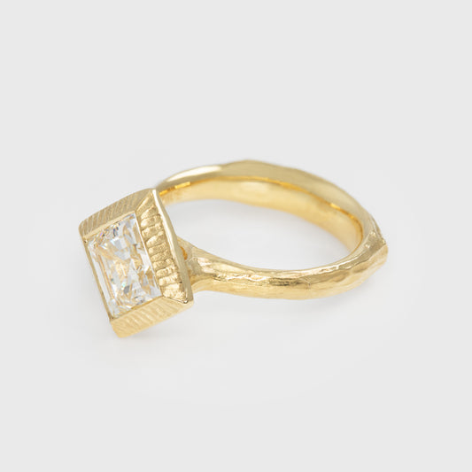Gold ring with diamond on a light gray background