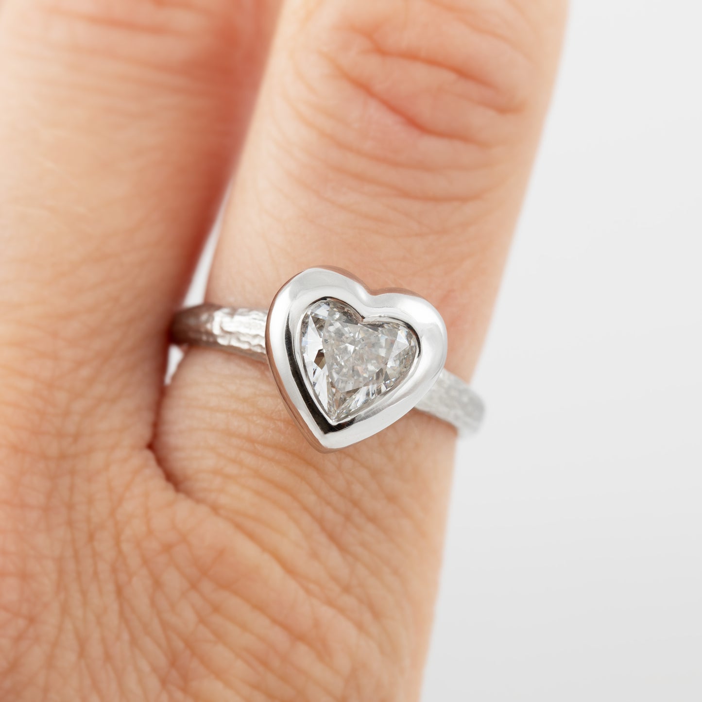 Platinum heart shaped diamond ring on a index finger