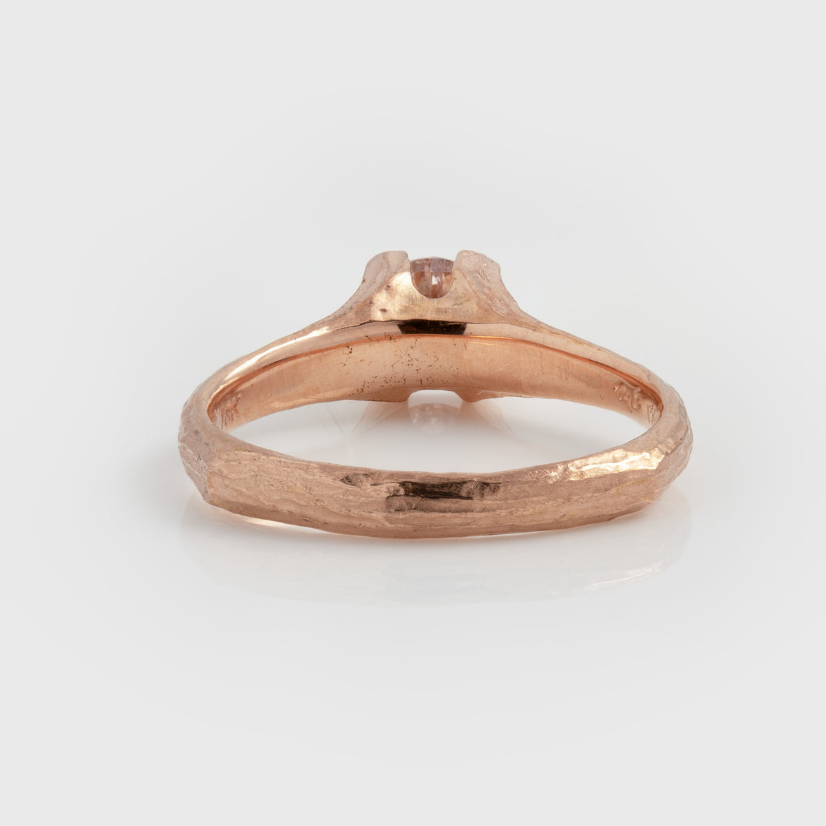Rear view of rose gold ring featuring a light pink diamond center stone and a textured band, photographed on a white background.
