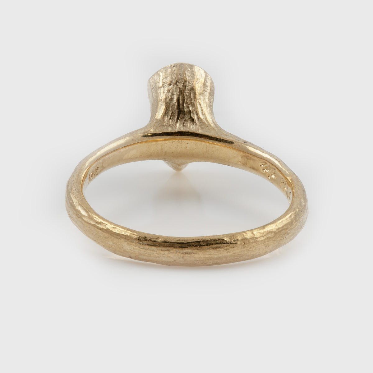 Rear view of yellow gold ring featuring a pear diamond center stone with a textured band, photographed on a white background.