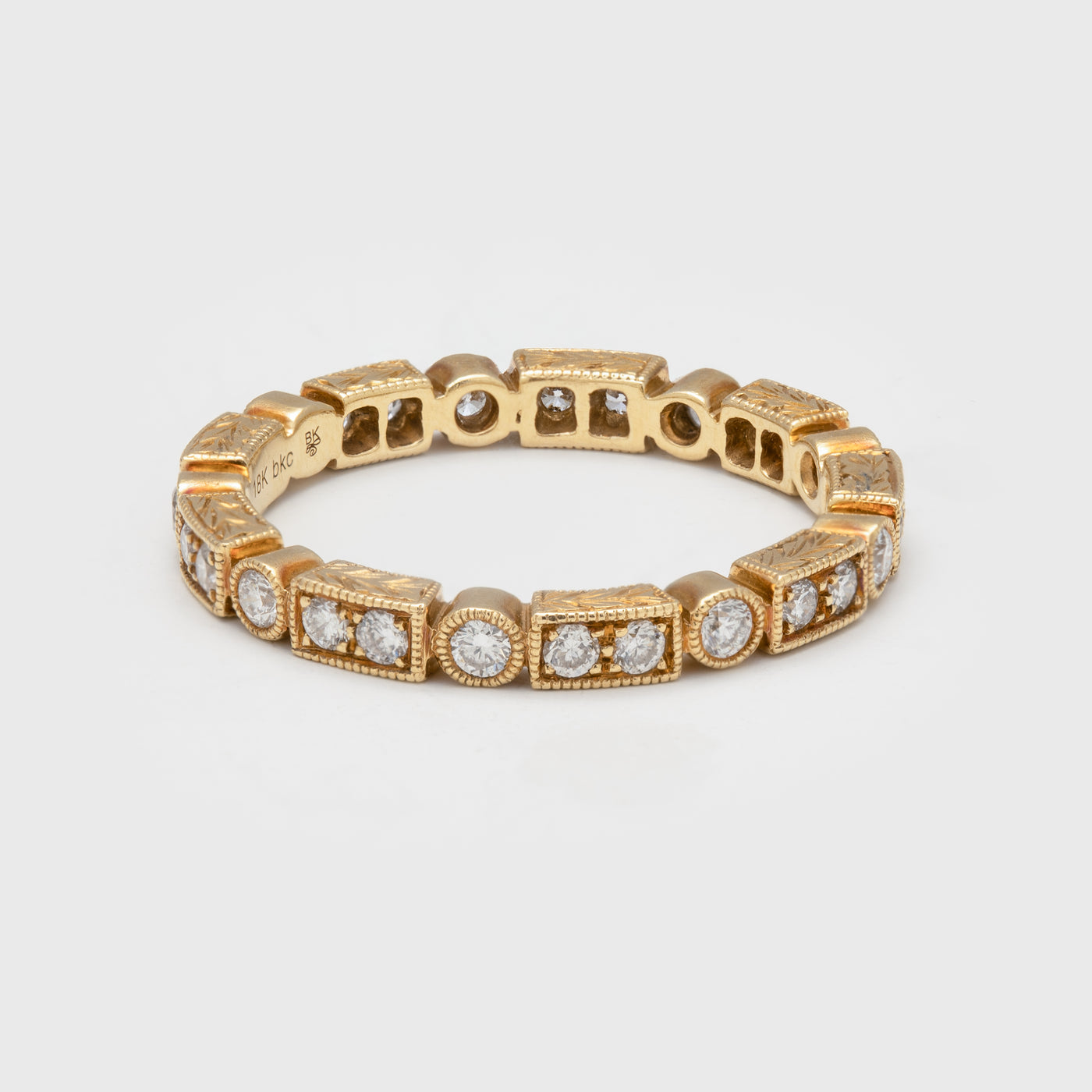 Close-up of an 18k yellow gold ring with diamonds and alternating rectangular shapes.