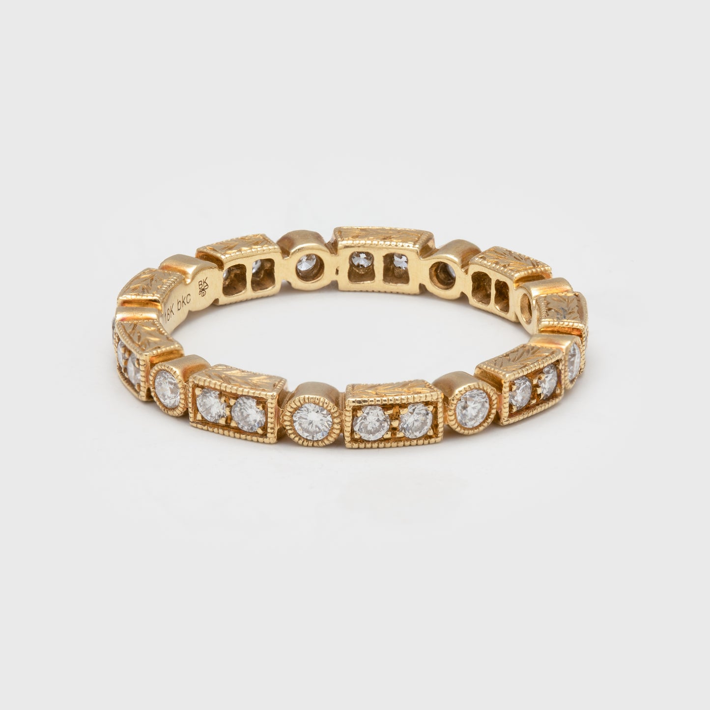 Close-up of an 18k yellow gold ring with diamonds and alternating rectangular shapes.