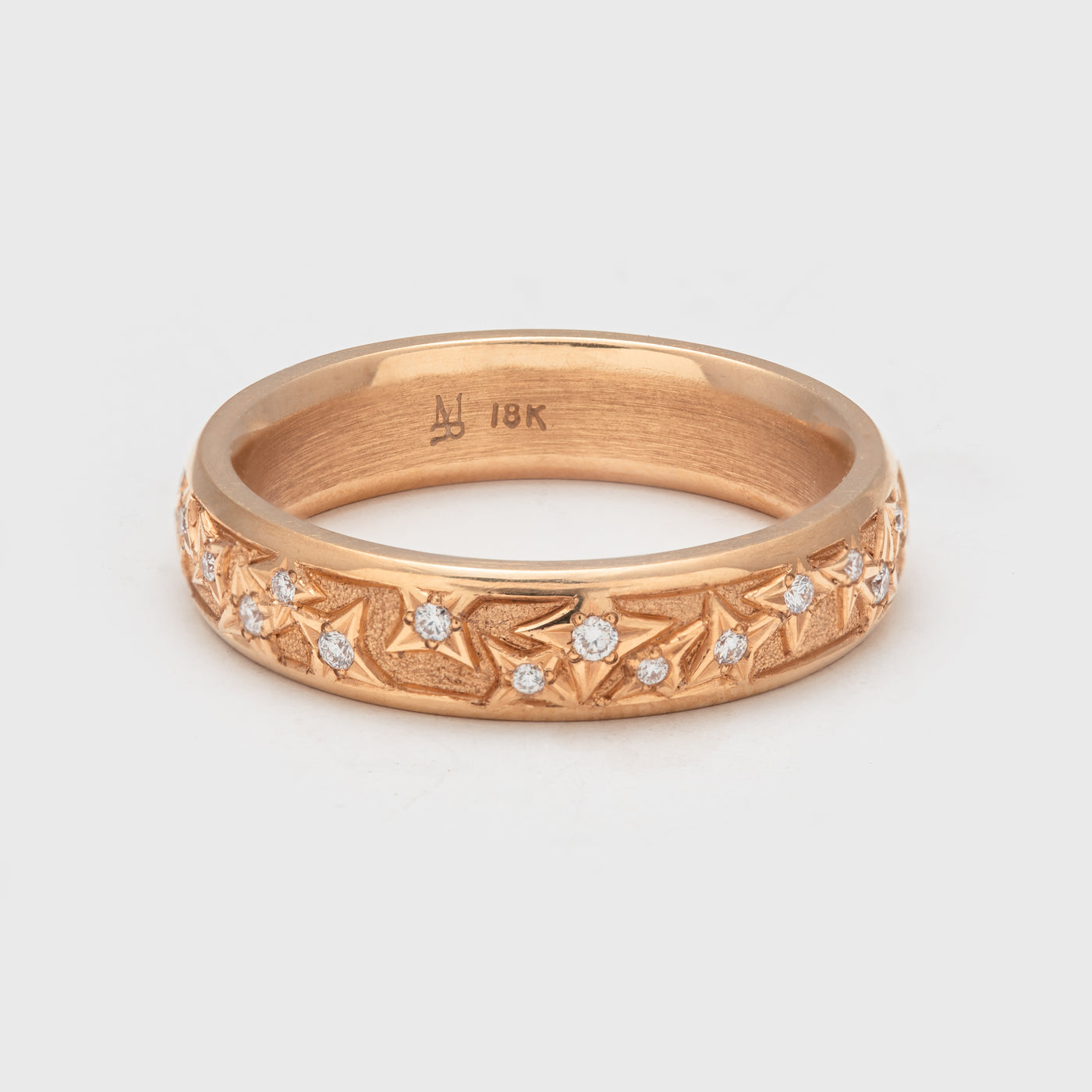 Close-up of an 18k rose gold band with round faceted diamonds.
