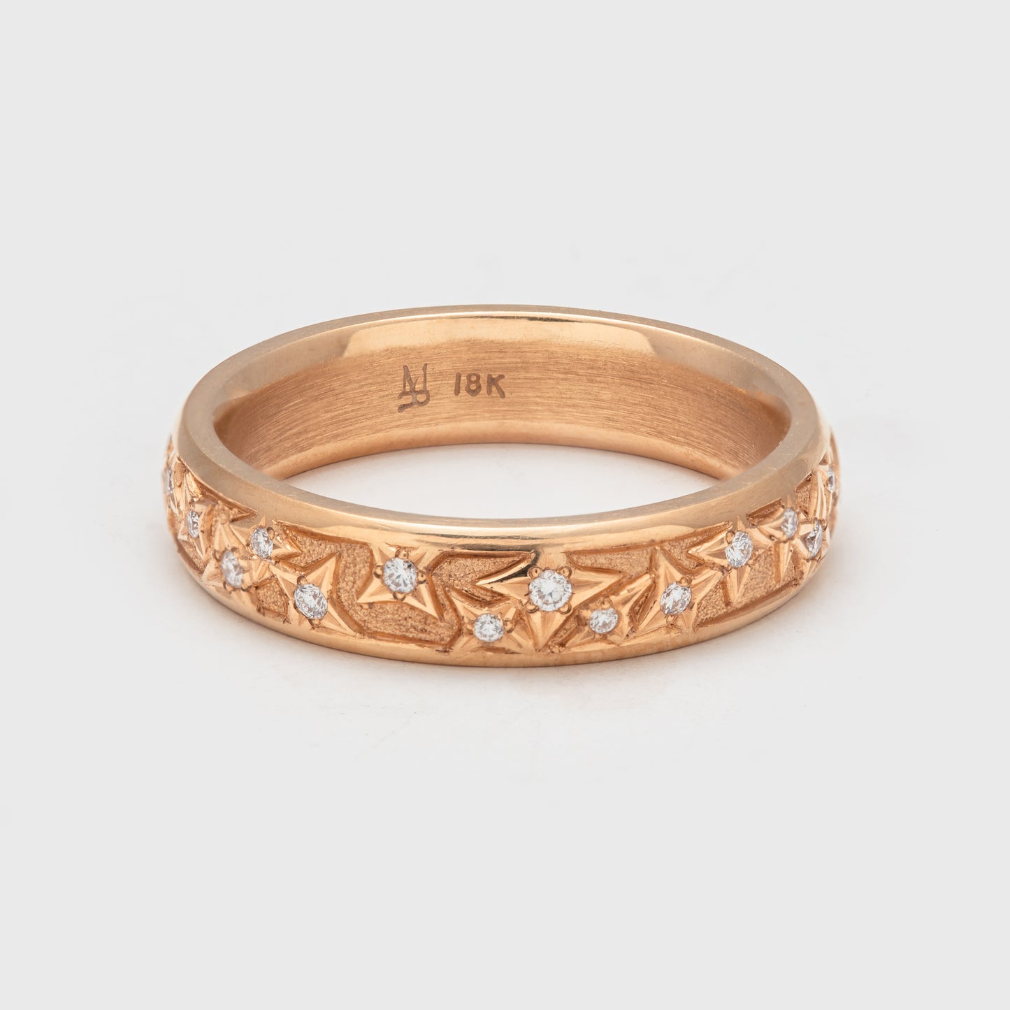 Close-up of an 18k rose gold band with round faceted diamonds.
