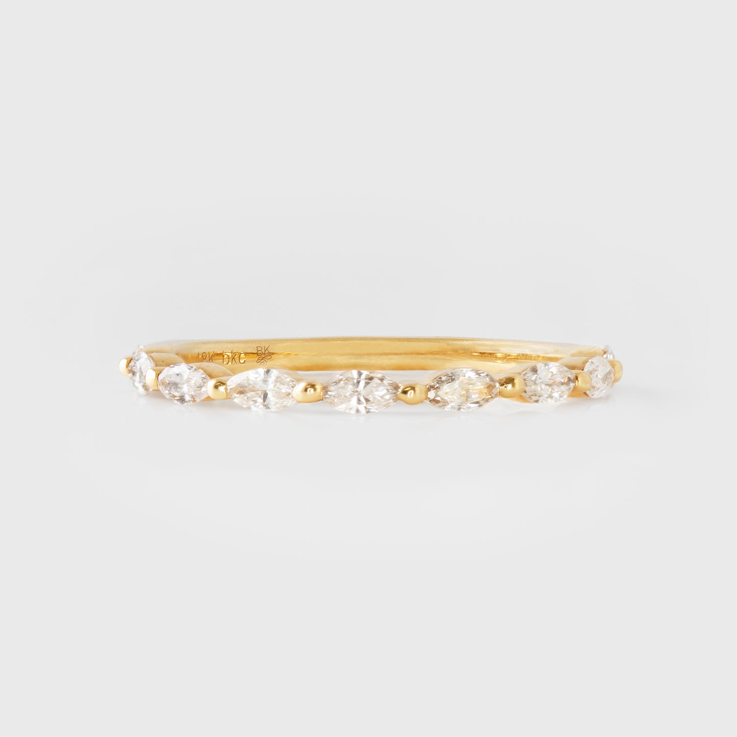 Gold ring with diamonds on a light gray background