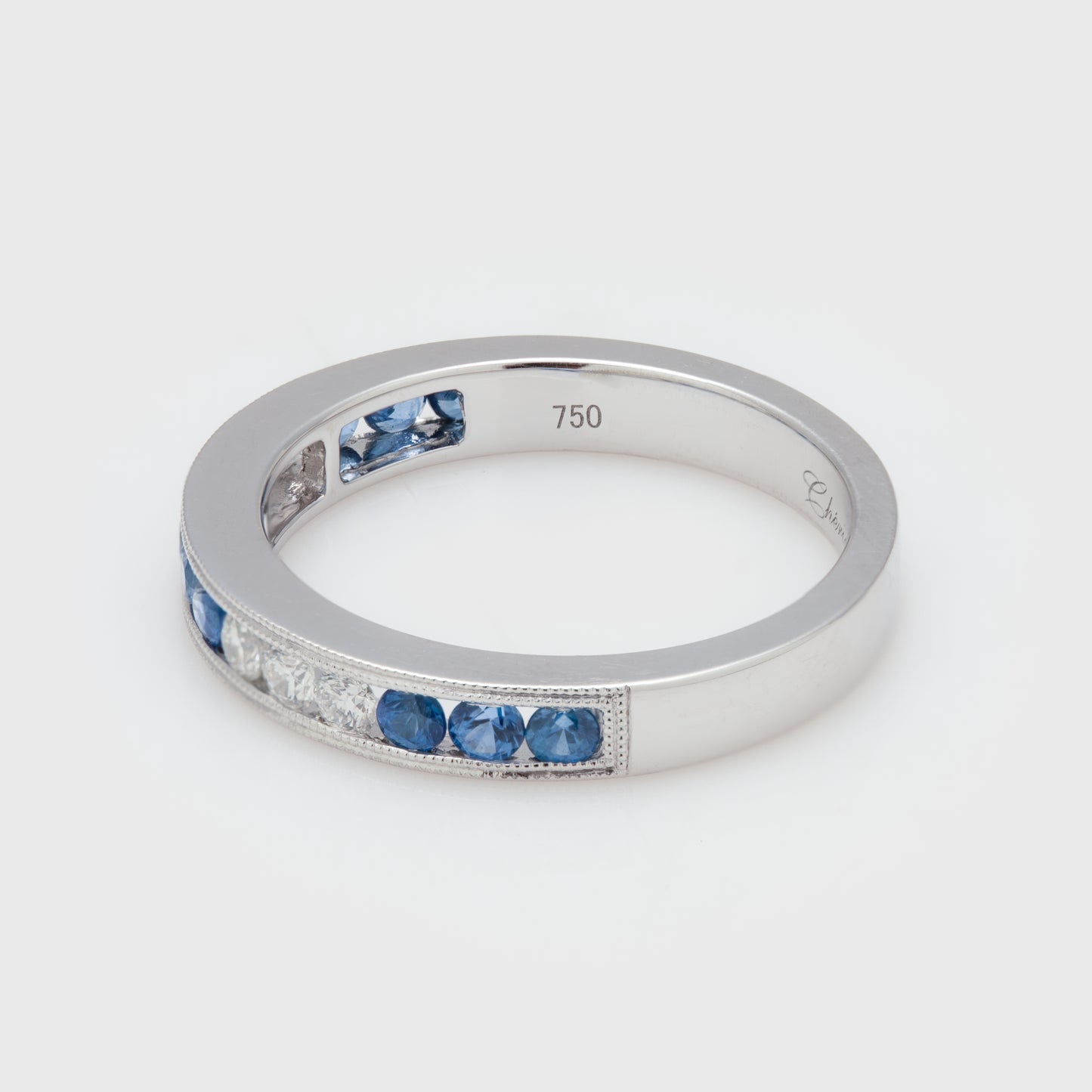 Side view of an 18k white gold band with round blue sapphires and round brilliant cut diamonds.