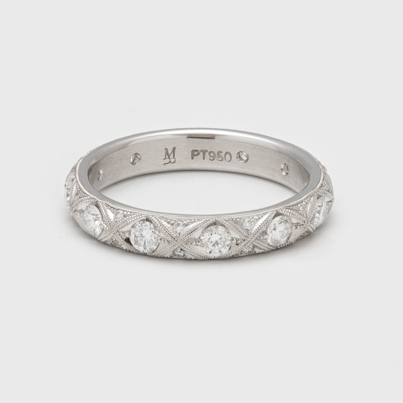 Close-up of a platinum ring with round diamonds and milgrain accents.