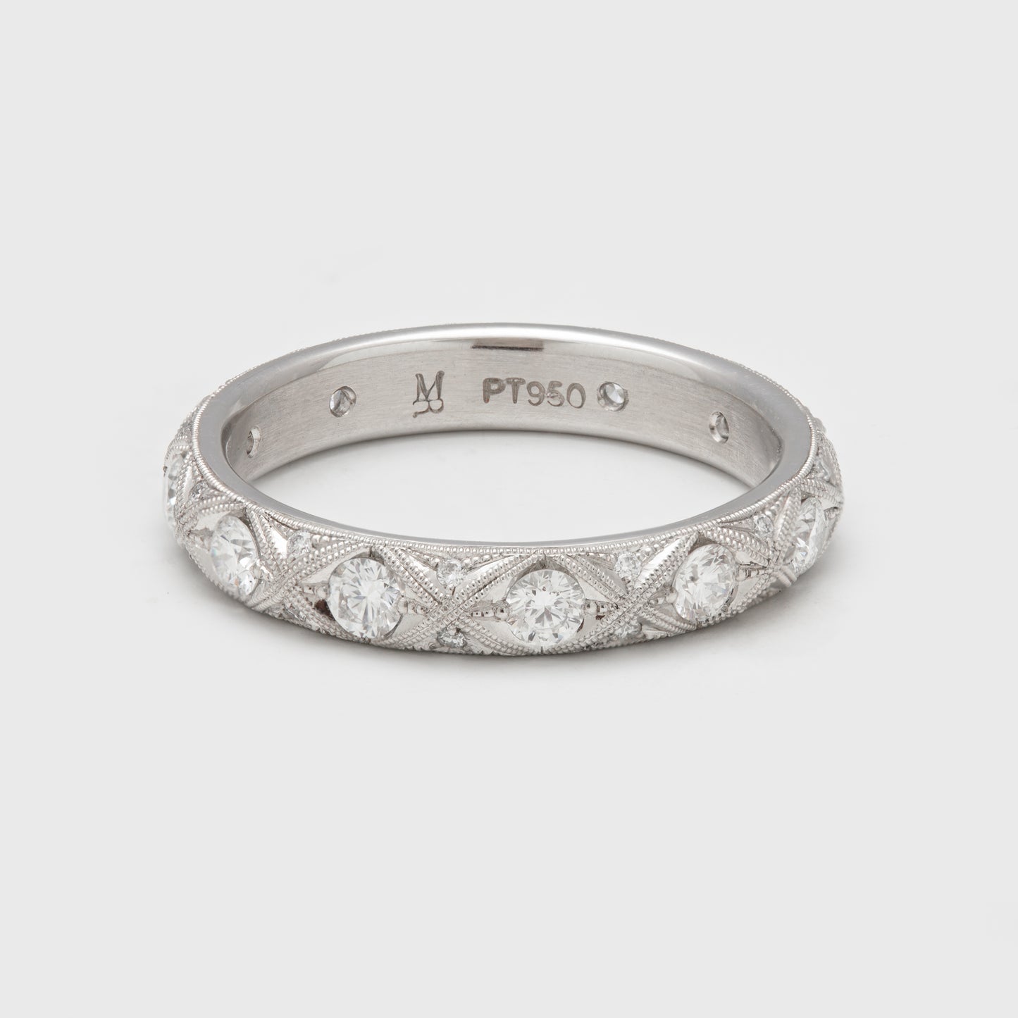 Close-up of a platinum ring with round diamonds and milgrain accents.