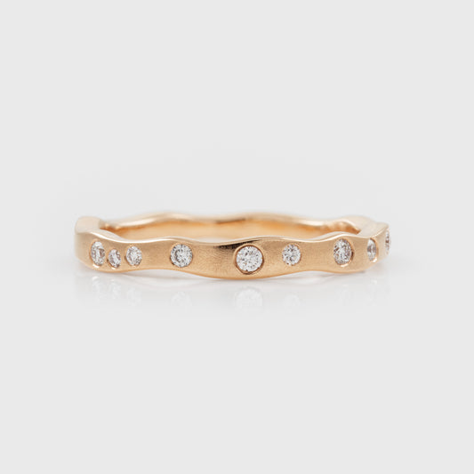 Rose gold ring with embedded diamonds on a light gray background