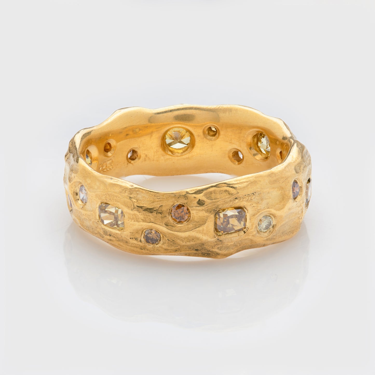 Close-up of a 22k yellow gold band with autumn colored diamonds.