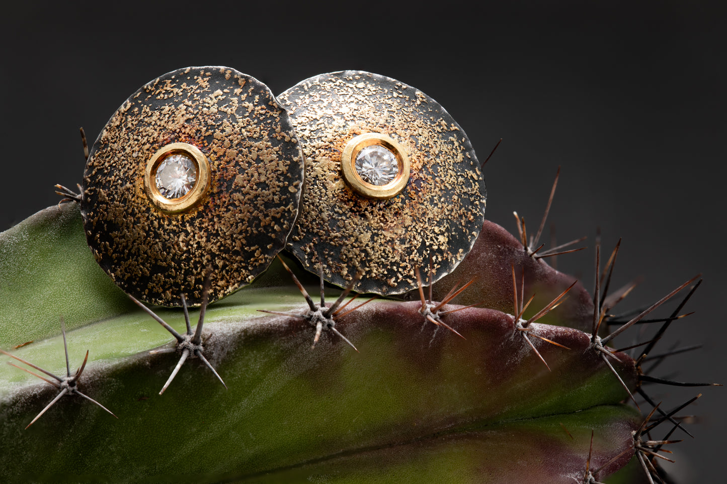 Close-up of sterling silver and yellow gold earrings with 22 karat yellow gold accents and diamonds.