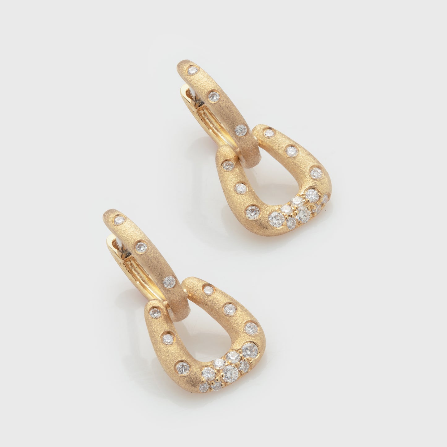 Close-up of 14k yellow gold earrings with a satin finish and diamonds.