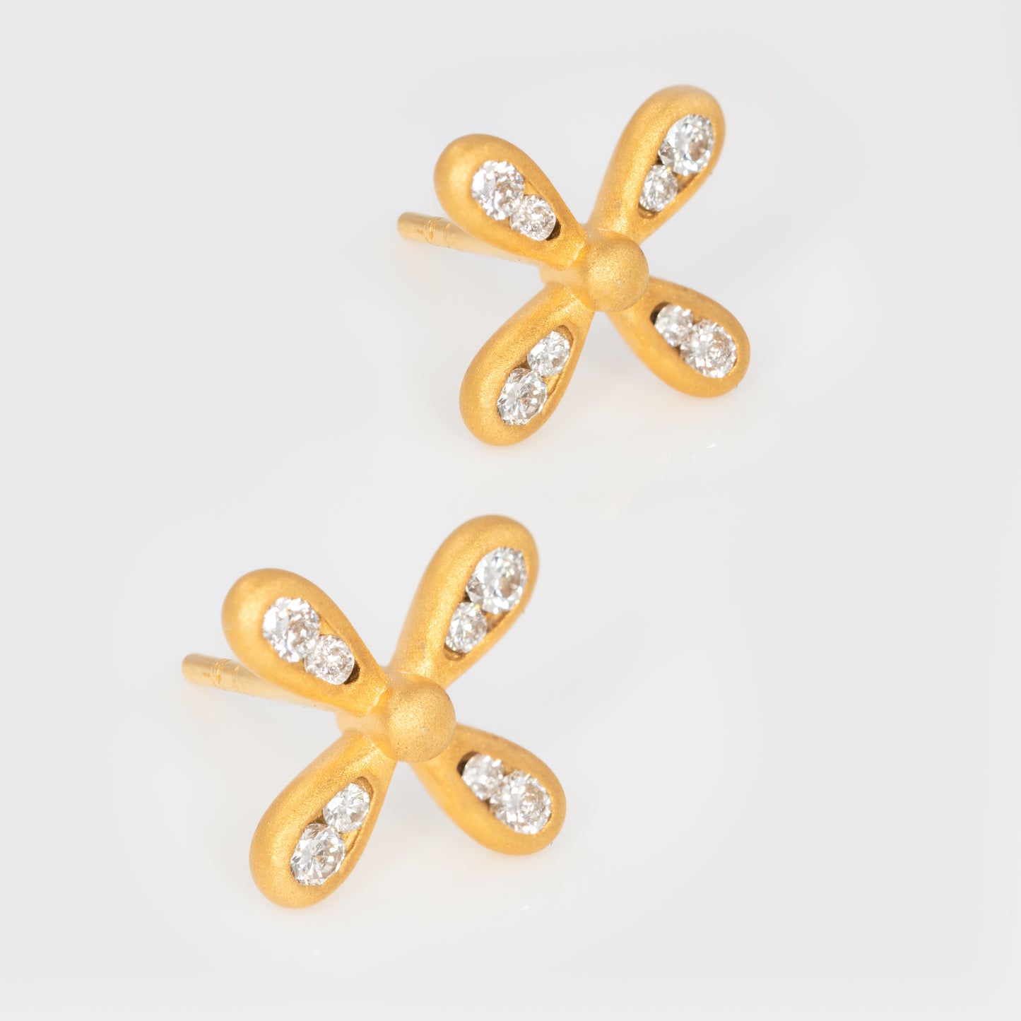 Close-up of 18k yellow gold studs with round diamonds.