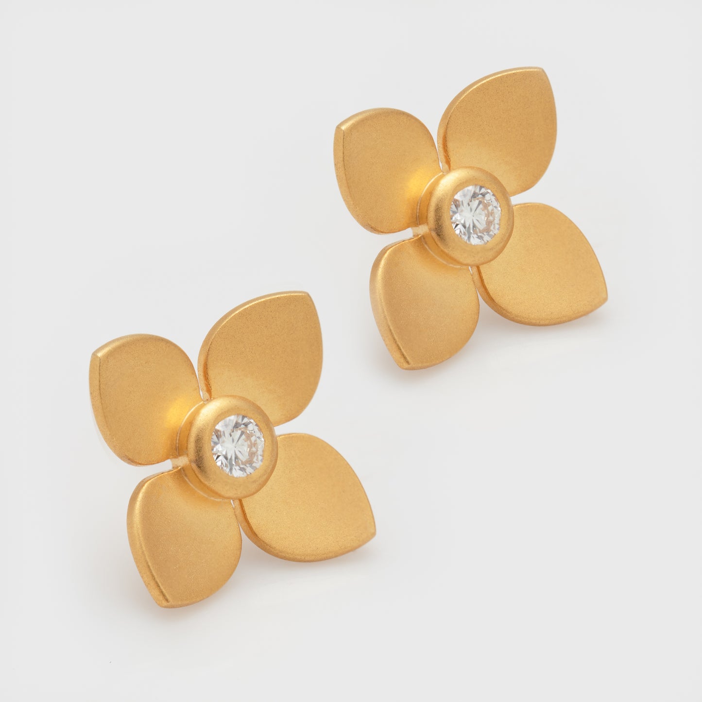 Close-up of 18k yellow gold flower earrings with diamonds and matte finish.