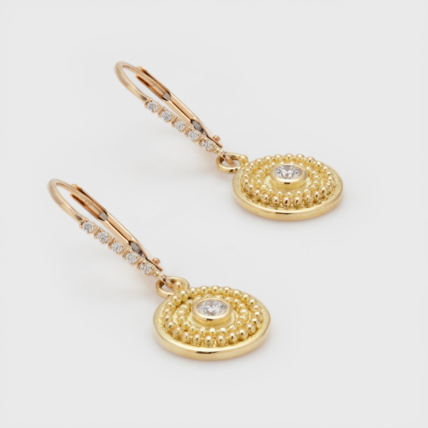 Close-up of "Small Disc" earrings by Cornelia Goldsmith, with 20k, 18k, and 14k yellow gold and round brilliant cut diamonds.