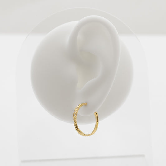 Gold hoop earring on a white ear model with a white background
