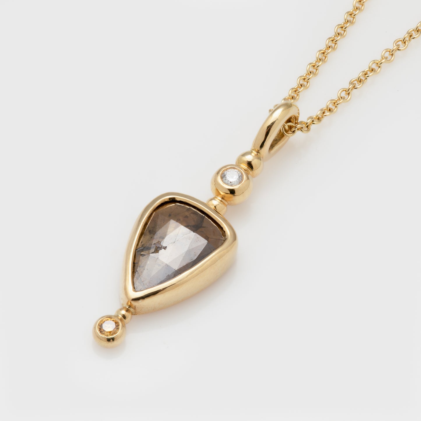 Close-up of an 18k yellow gold necklace with rose cut champagne diamond and yellow and white diamonds.