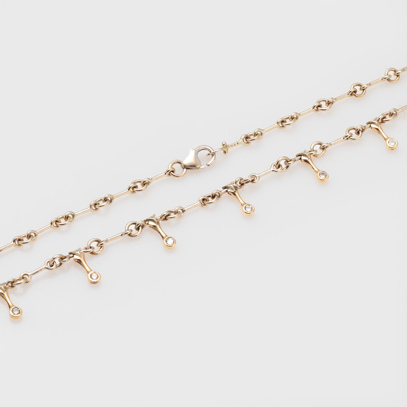 Side view of a 14k bicolor gold necklace with diamonds.