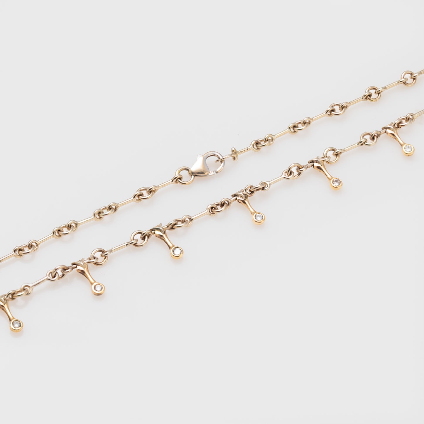 Side view of a 14k bicolor gold necklace with diamonds.