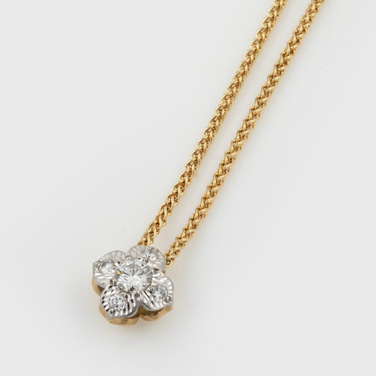 Two-tone flower pendant featuring diamonds, suspended from a yellow gold chain, photographed on a white background.