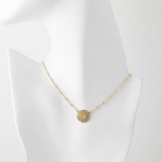 Gold necklace with a circular pendant on a mannequin bust against a white background