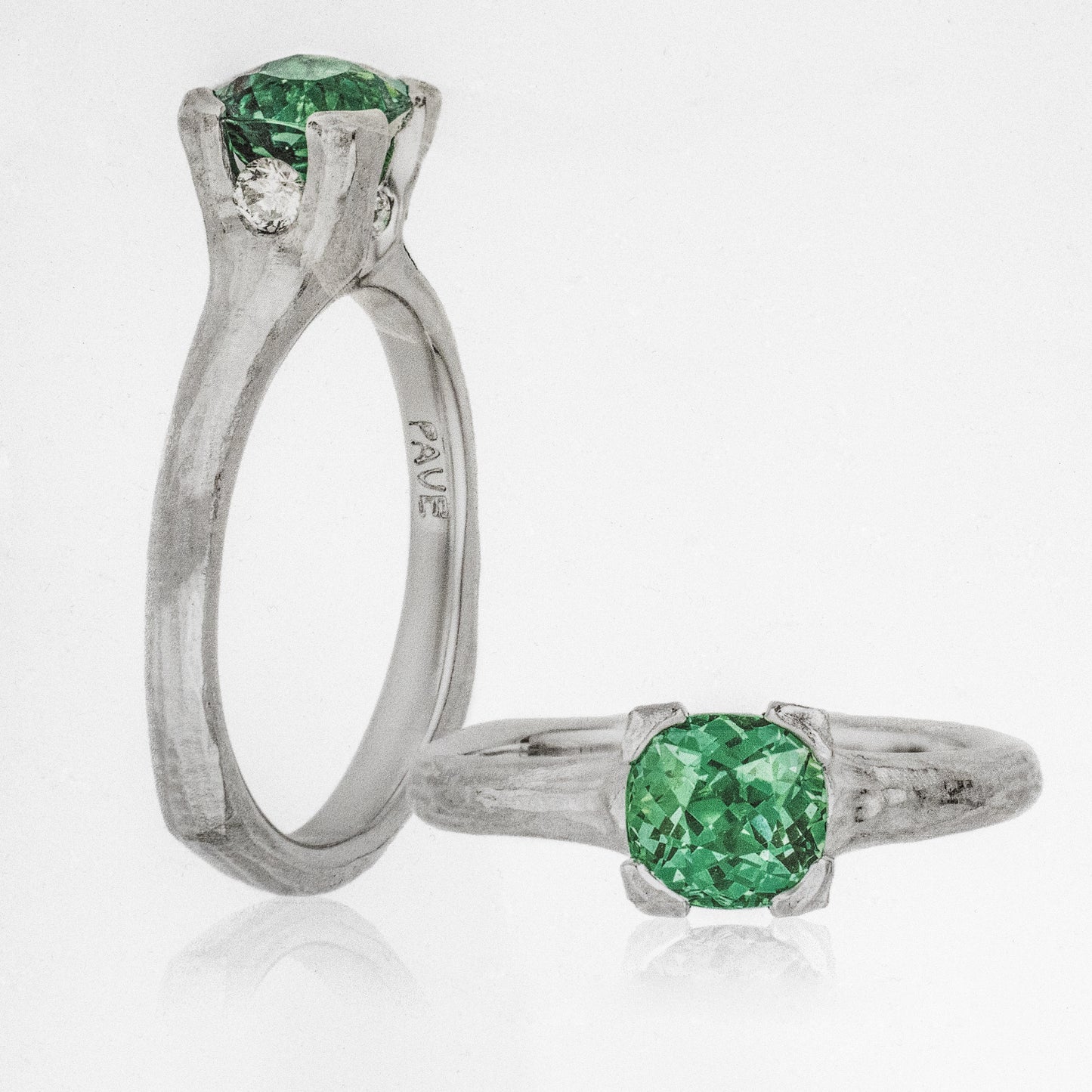 A platinum ring with a redwood bark design, featuring a central tsavorite garnet gemstone, surrounded by round brilliant diamonds, with a squared band shape.