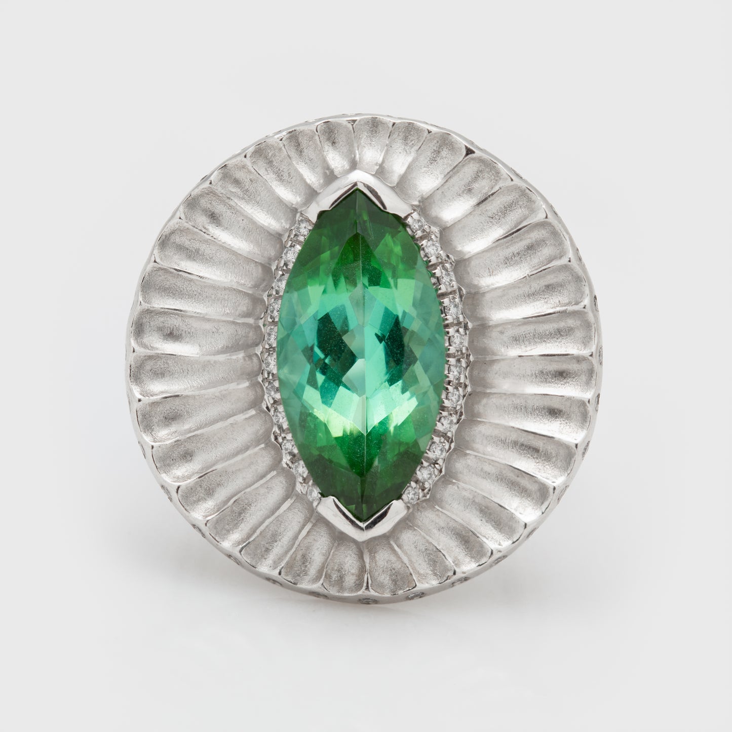 Close-up of platinum ring with a marquise-cut green tourmaline and round brilliant cut diamonds.
