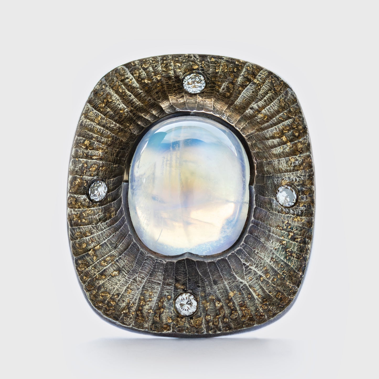 Close-up of textured Argentium silver ring with rainbow moonstone and four accent diamonds, featuring 22k gold dust and a hidden diamond.