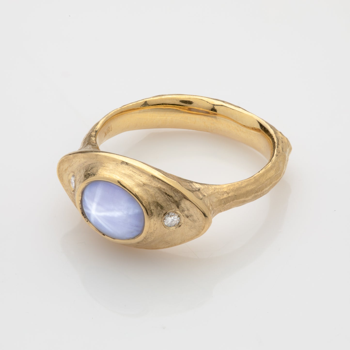 Side view of an 18k yellow royal gold ring with a pale gray-blue Star Sapphire and diamonds.