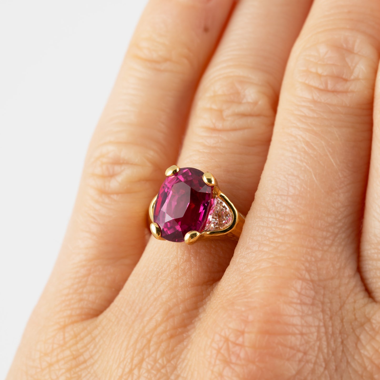 Pinkish red ruby ring with side diamond on a hand.