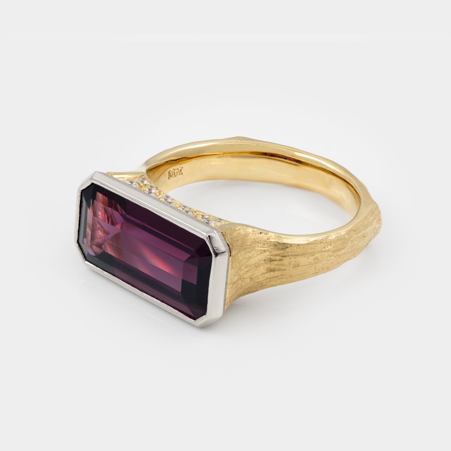 Gold ring with a purple gemstone on a white background