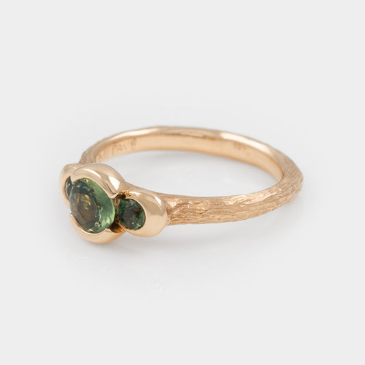 Gold ring with green gemstones on a white background