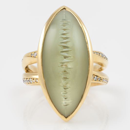 Gold ring with a light green marquise-shaped gemstone and small diamonds on the band.
