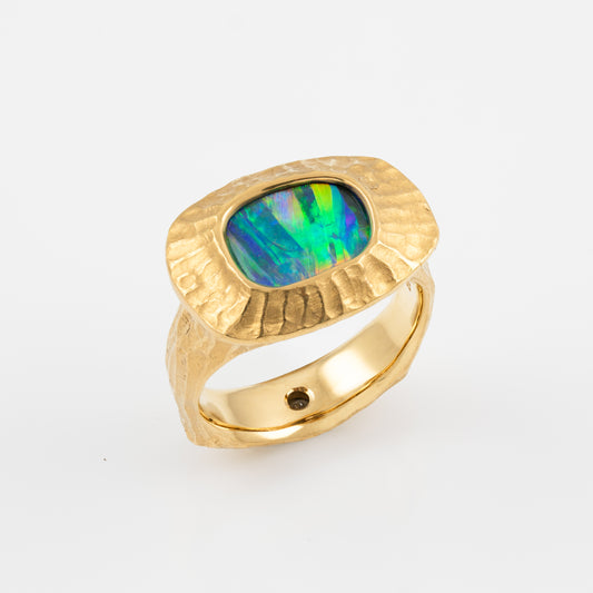 Gold ring with a colorful boulder opal gemstone on a white background