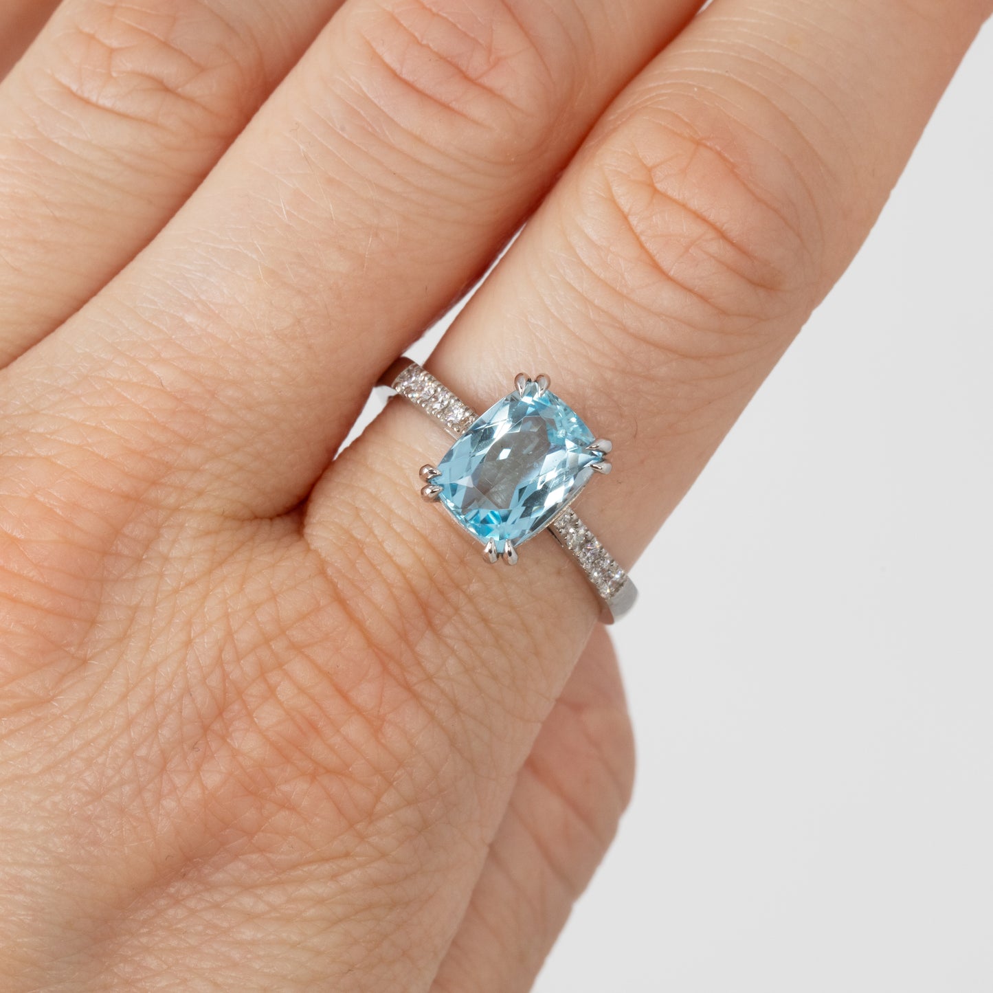 Ring with a blue gemstone on a finger against a white background