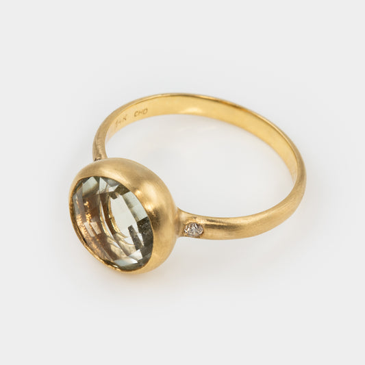Gold ring with a large green amethyst gemstine on a white background, three-fourths angle