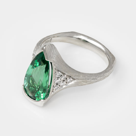 Platinum ring with a green gemstone on a white background