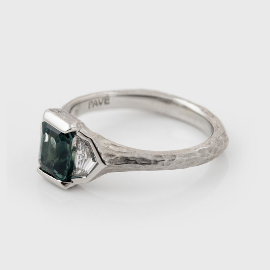 Platinum ring with green center gemstone and two accent diamonds on a white background