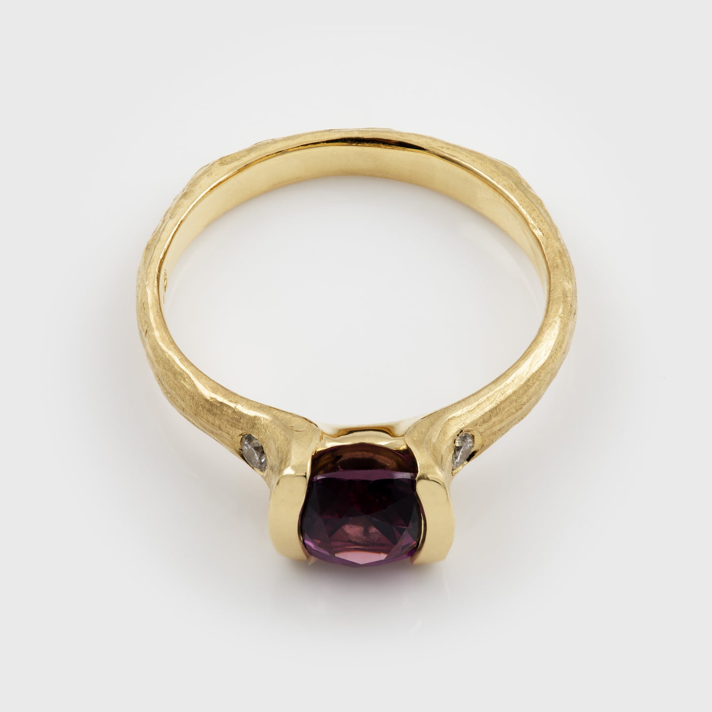 Gold ring with a purple gemstone on a white background