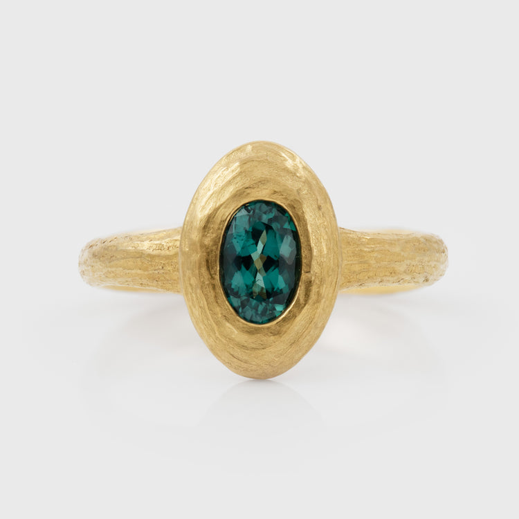 Gold ring with a green Alexandrite gemstone on a white background