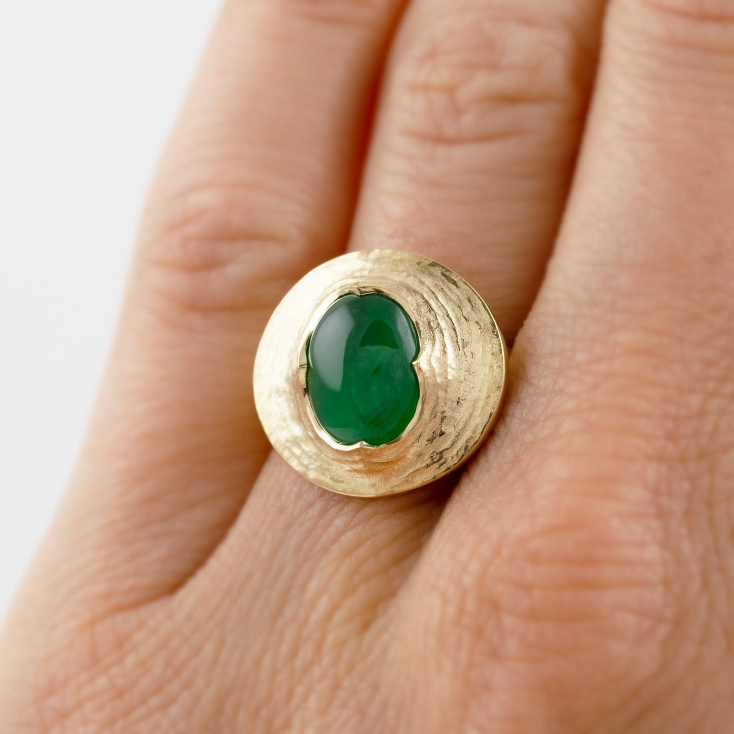 Yellow gold ring featuring oval cabochon green Jade worn on a hand