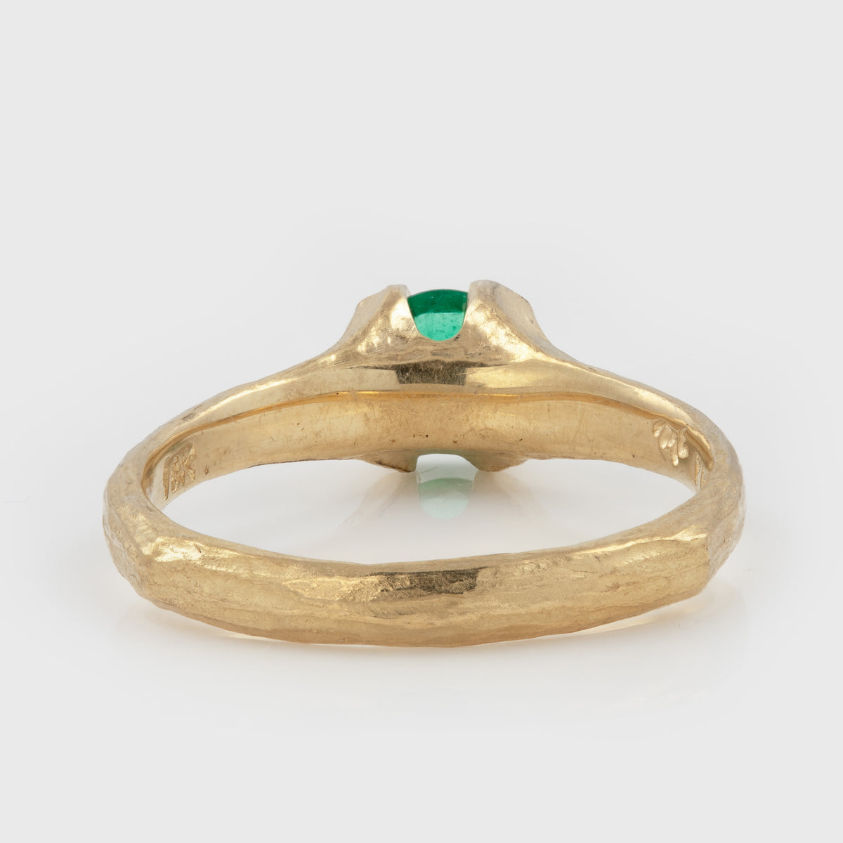 Back view of yellow gold ring featuring a round green stone and a textured band, photographed on a white background.